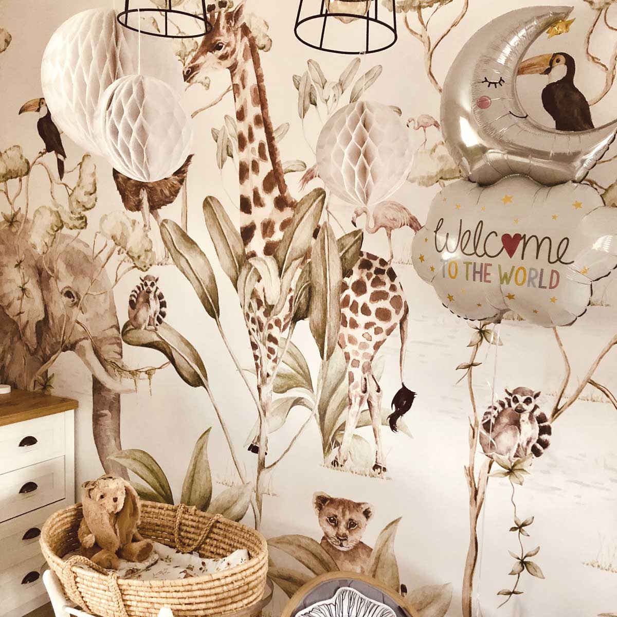 Dekornik Savanna Behang — Een speels behang met savanne-diertjes zoals giraffen, leeuwen en olifanten tussen gras en bomen, in warme zandtinten, perfect voor een avontuurlijke kinderkamer. Sfeerbeeld van het behang in een ingerichte kinderkamer.