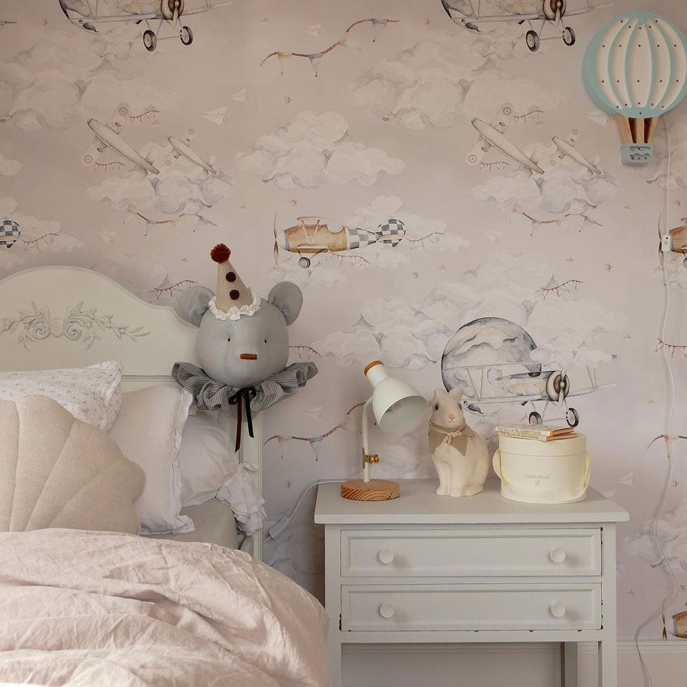 Dekornik Magic Planes Behang — Een avontuurlijk behang met magische vliegtuigjes die tussen wolken en sterren zweven, perfect voor een dromerige, speelse kinderkamer. Sfeerbeeld van het behang in een ingerichte kinderkamer.