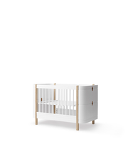 Oliver Furniture Wood Mini+ Cot Bed White/Oak in white/oak in een rustige Scandinavische babykamer met naturel houten vloer
