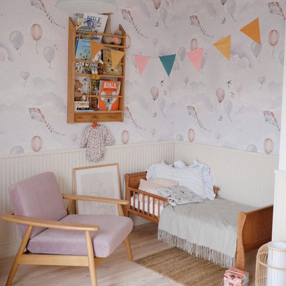 Dekornik Balloons Fairytale Behang — Een sprookjesachtig behang met luchtballonnen die over een dromerige hemel zweven, in zachte kleuren, perfect voor een magische kinderkamer. Sfeerbeeld van het behang in een ingerichte kinderkamer.