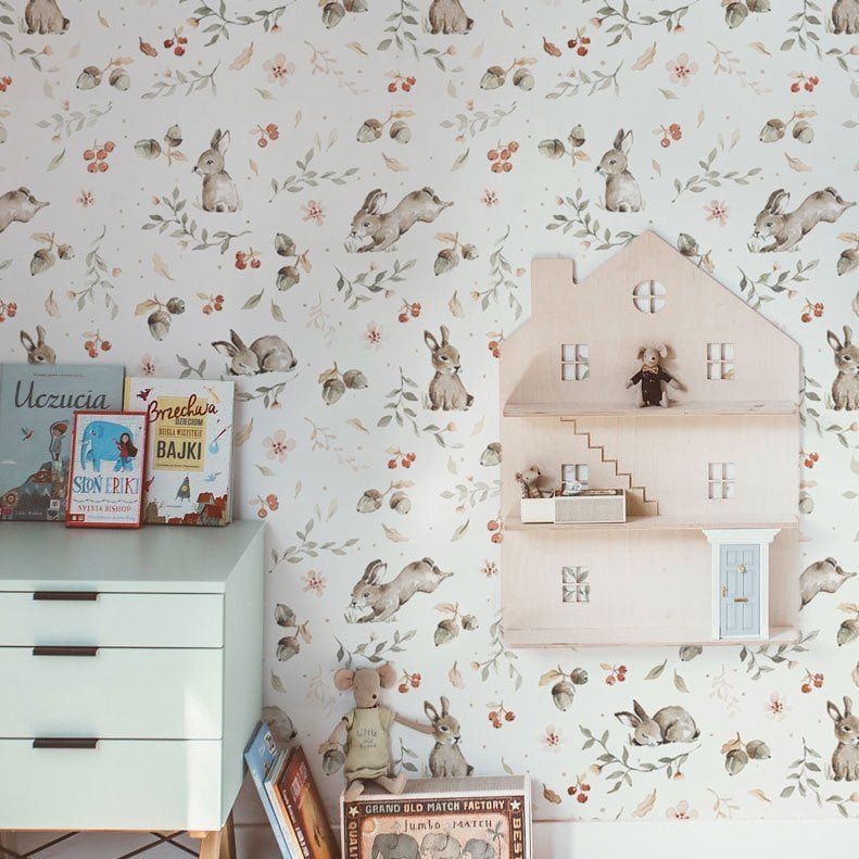 Dekornik Happy Rabbits Behang — Een vrolijk behang met huppelende konijntjes tussen bloemen en gras, in zachte kleuren, perfect voor een lieve, speelse kinderkamer. Sfeerbeeld van het behang in een ingerichte kinderkamer.