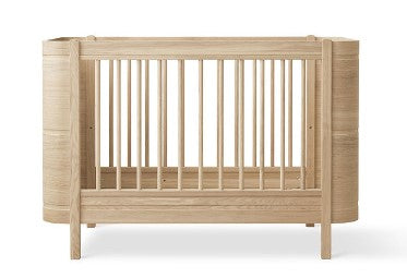 Oliver Furniture Wood Mini+ Cot Bed Incl. Junior Kit Oak opgesteld in een lichte Scandinavische kinderkamer