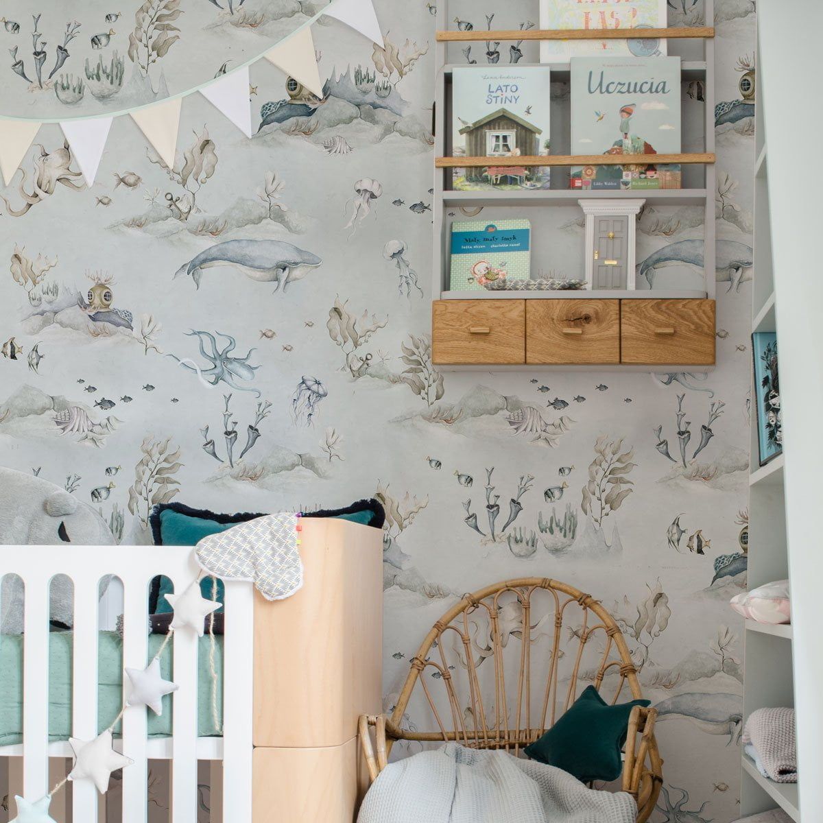 Dekornik Underwater World Grey Behang — Een sfeervol behang met een onderwaterwereld vol visjes en zeewezens op een grijze achtergrond, perfect voor een rustige, maritieme kinderkamer. Sfeerbeeld van het behang in een ingerichte kinderkamer.