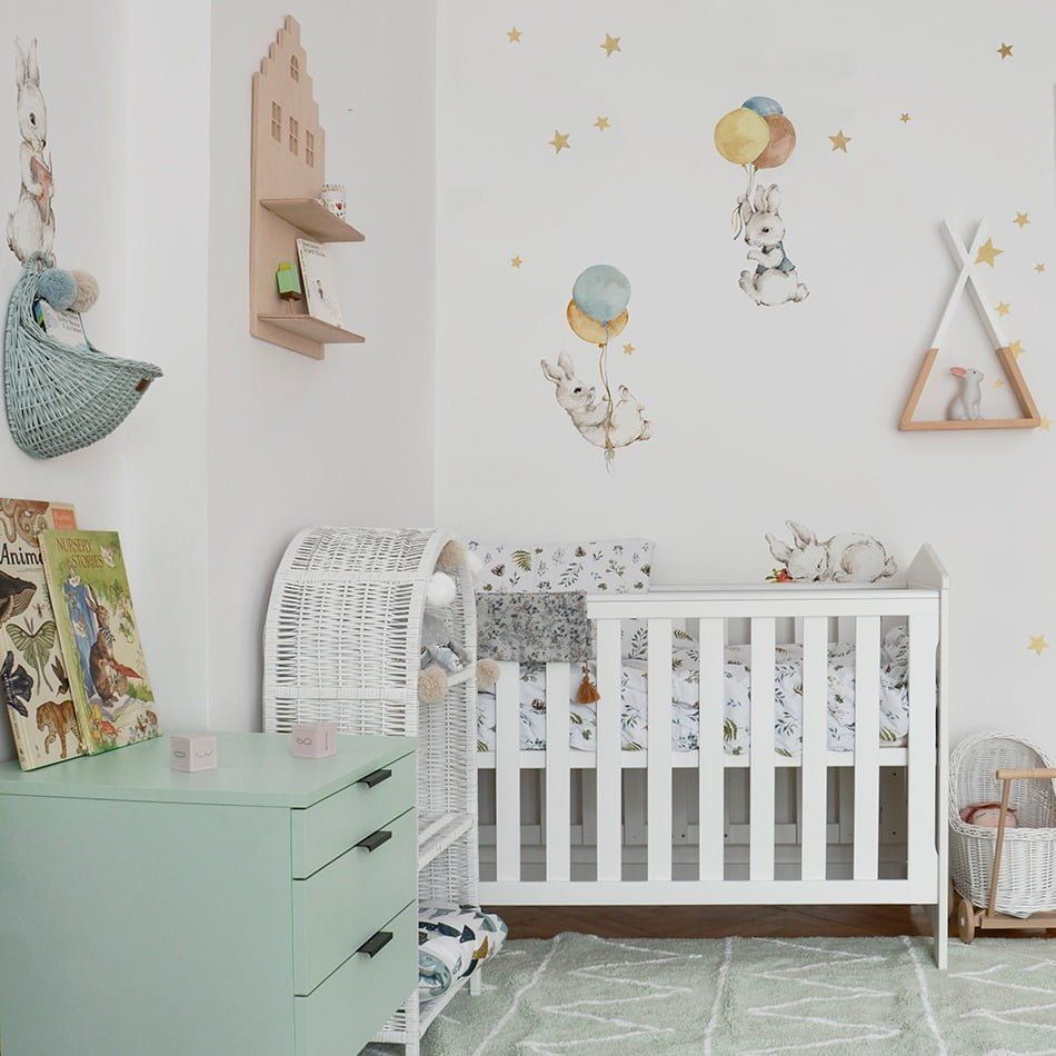 Dekornik muursticker White Happy Rabbits Wonderland Set met 8 witte konijntjes in pastelkleuren op een lichte kinderkamermuur